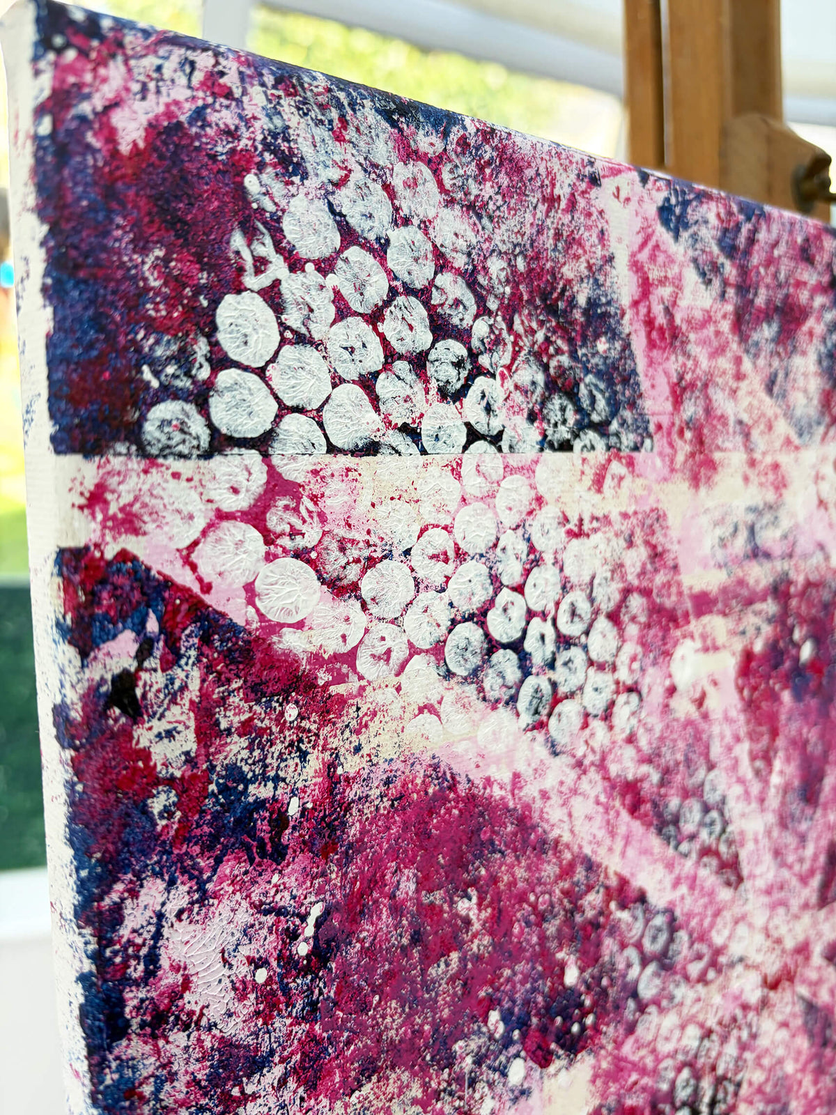 Detailed angled view of Pop & Circumstance II showing white circular patterns over deep pink, magenta and dark blue textured layers.