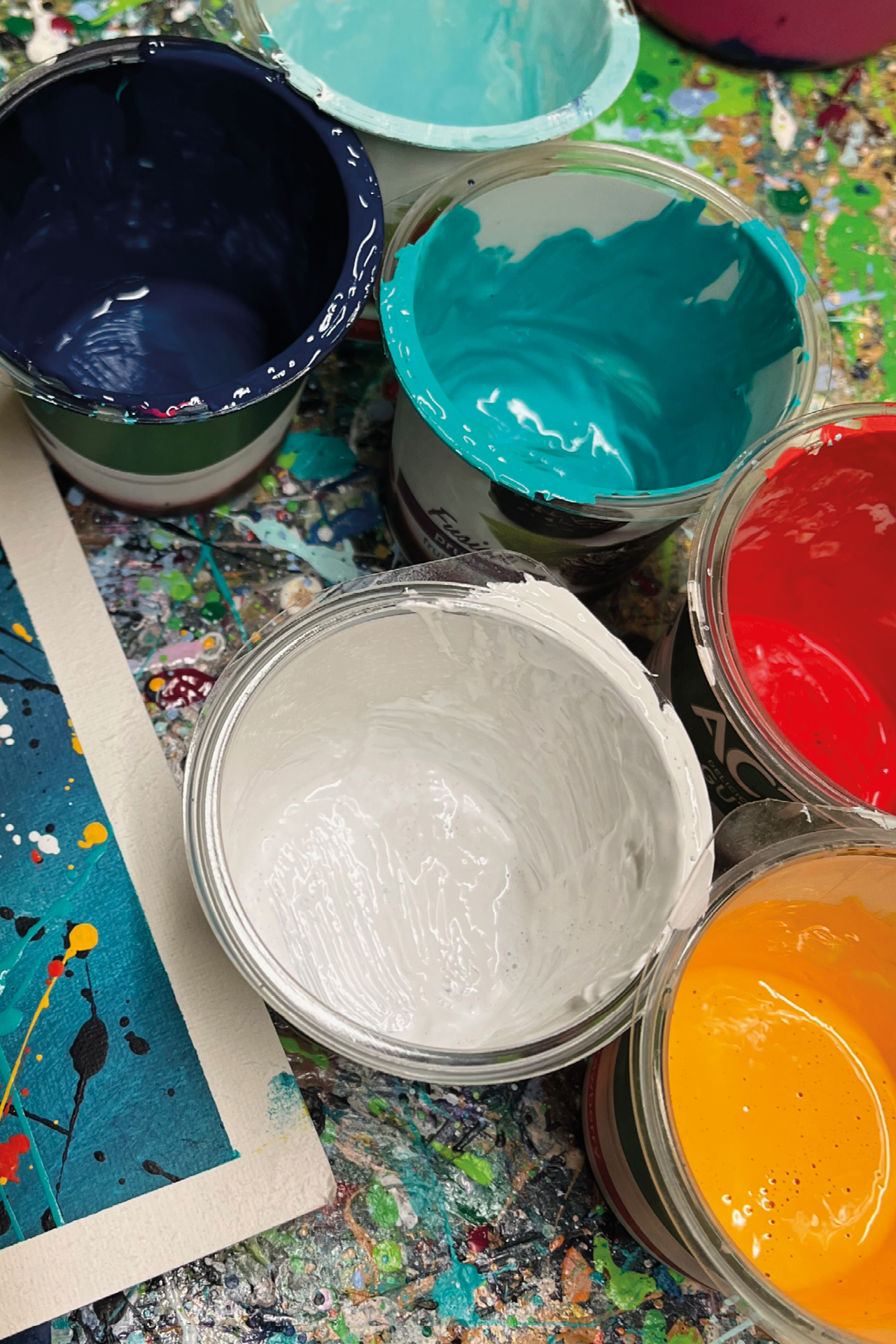 Five plastic pots containing branding colours of white, teal, light teal, red, orand and dark blue.