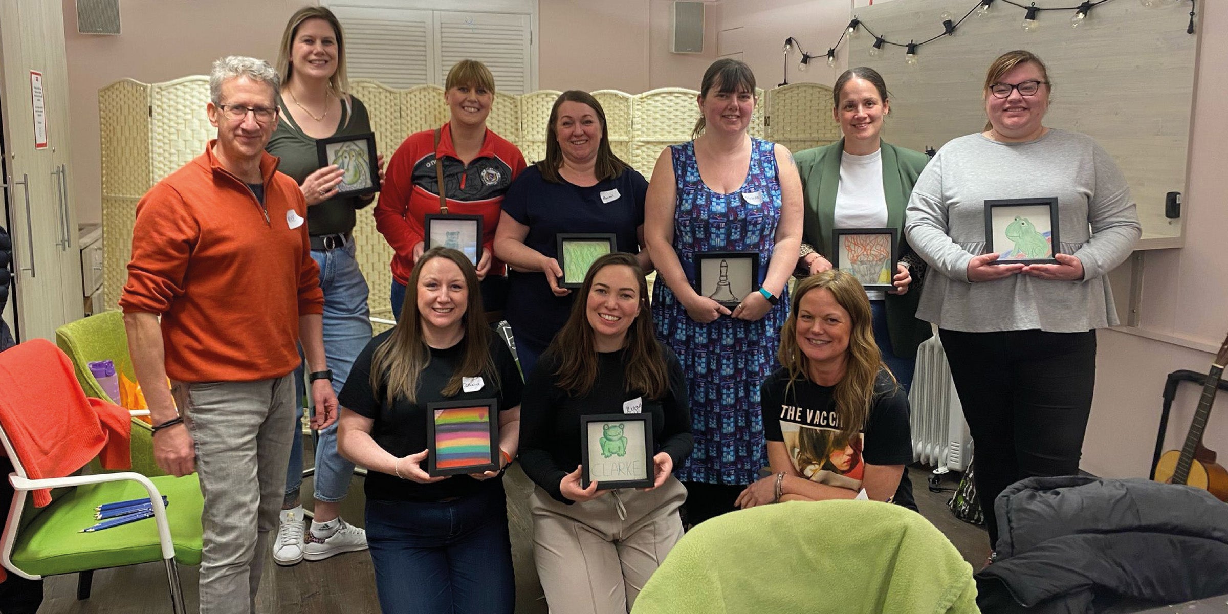 Participants proudly holding artwork created during a creative session